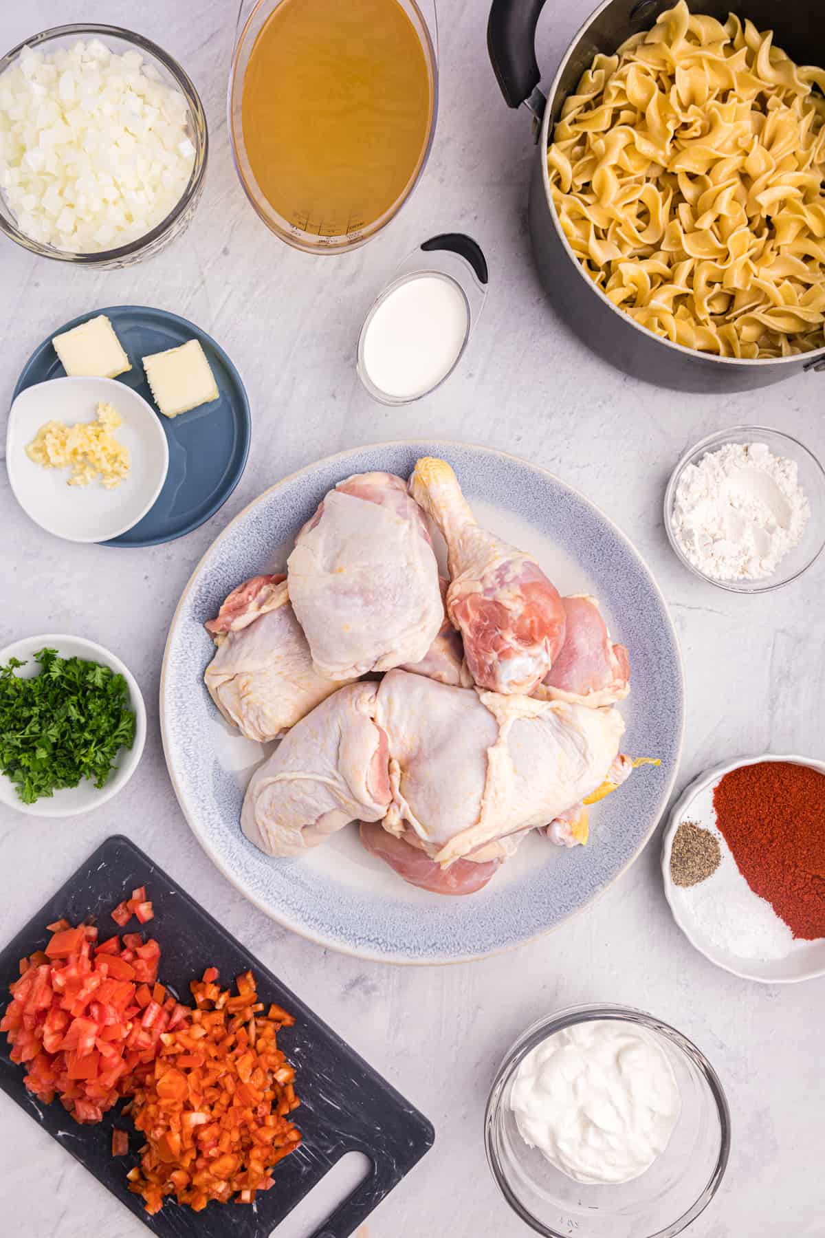 The ingredients for chicken paprikash are placed on a white surface.
