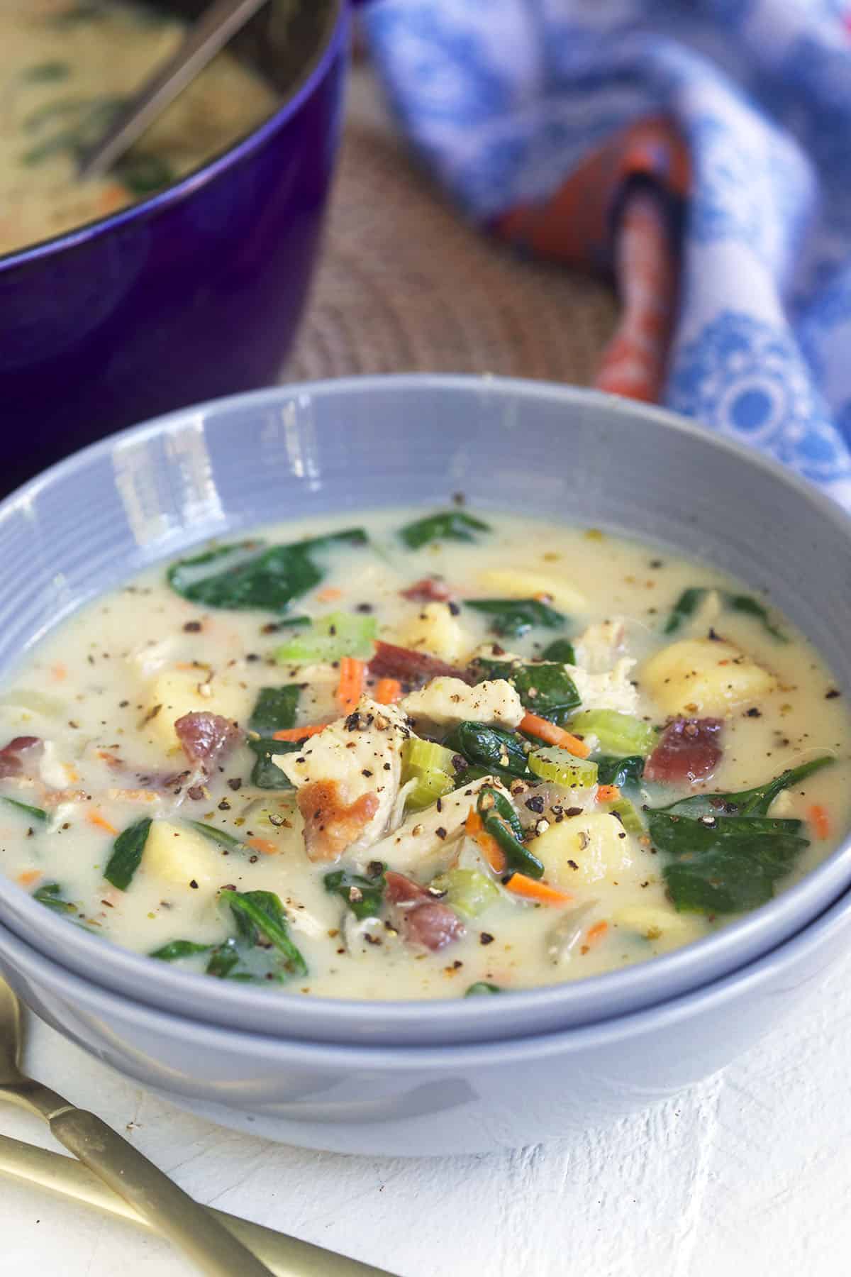 A blue bowl is filled with chicken gnocchi soup.