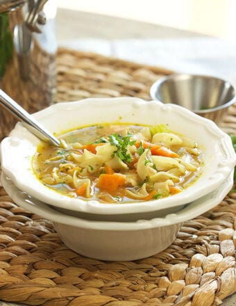 Chicken Noodle Soup in a white bowl on a wicker place mat.