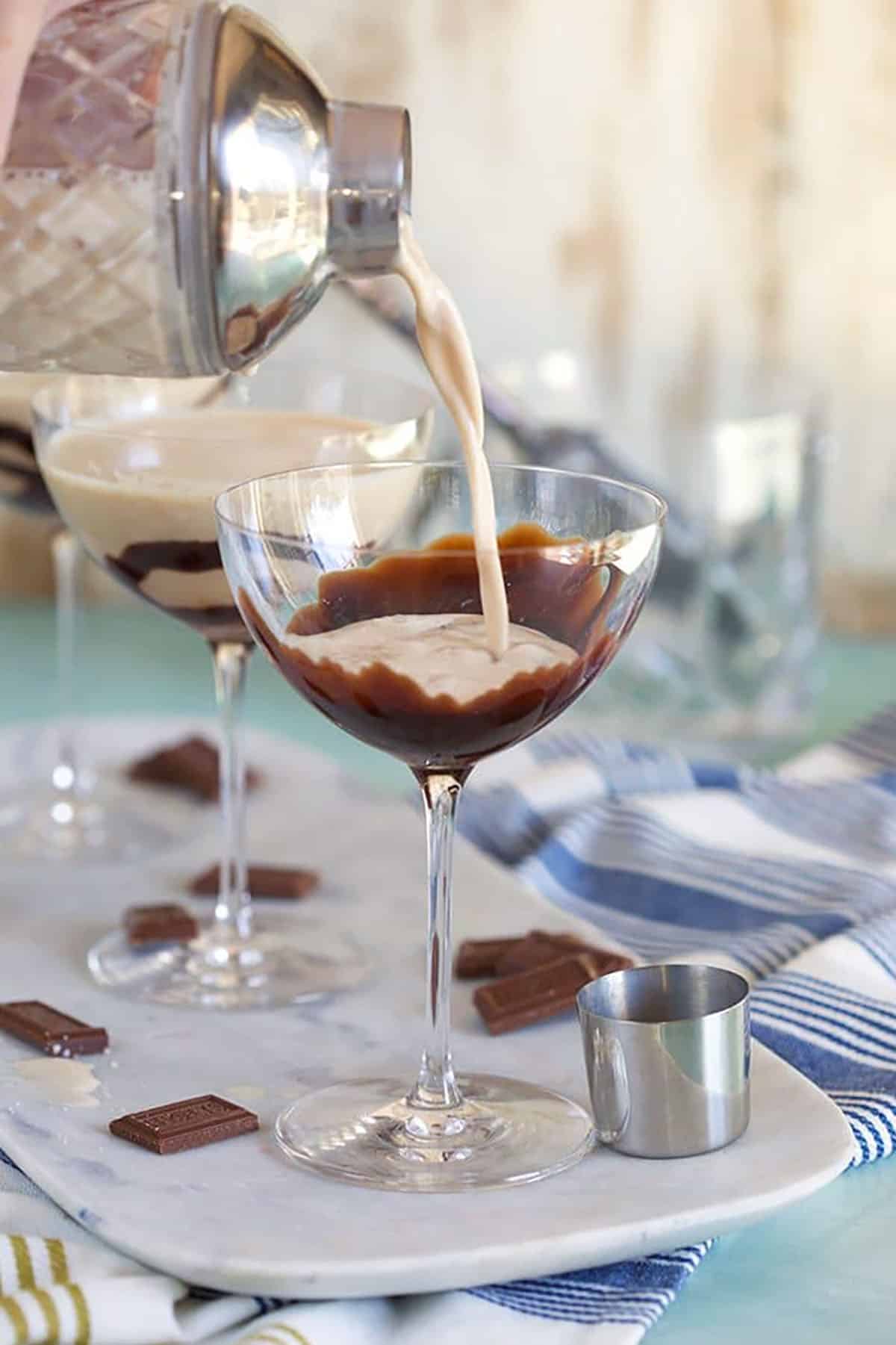 Chocolate Martini being poured into a martini glass with chocolate sauce swirled in the glass.