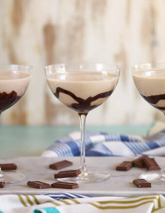 Three chocolate martinis lined in a row on a marble platter.