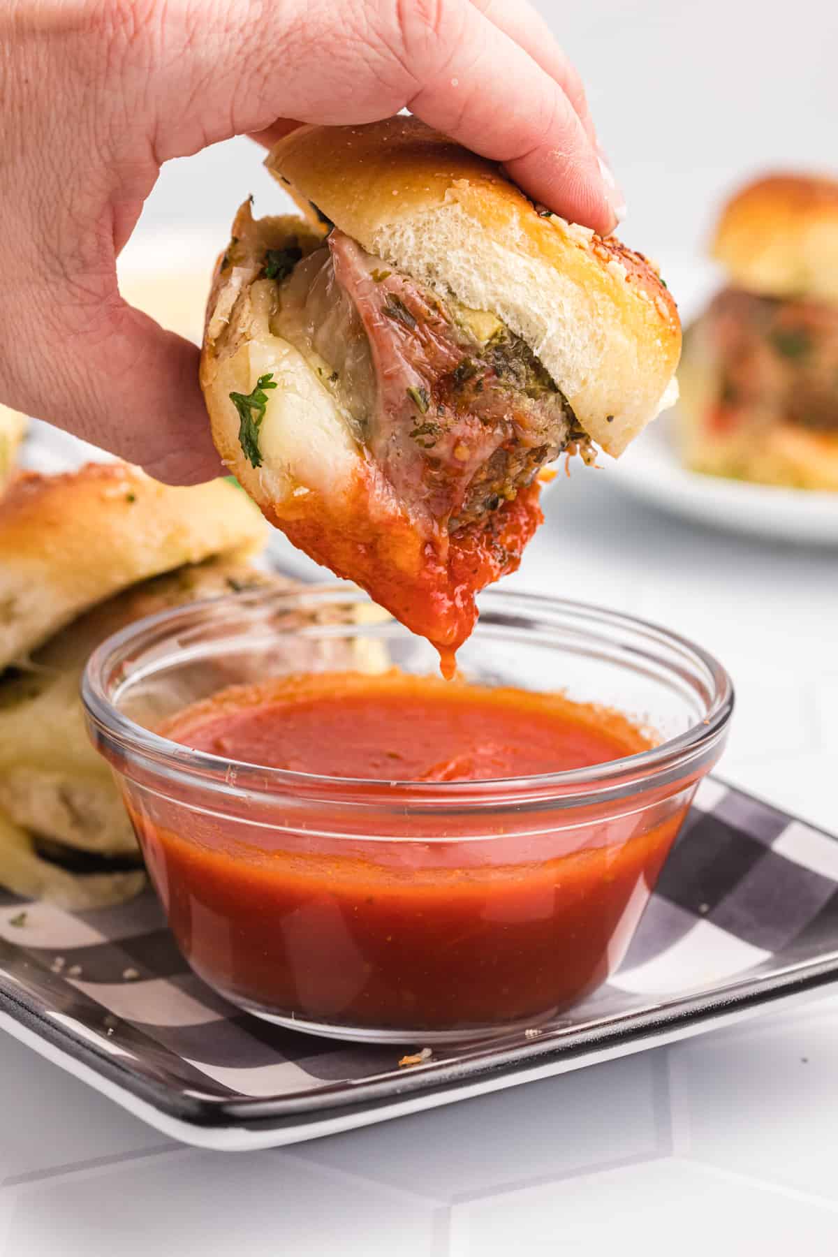 Meatball Slider being dipped into a glass bowl of marinara.