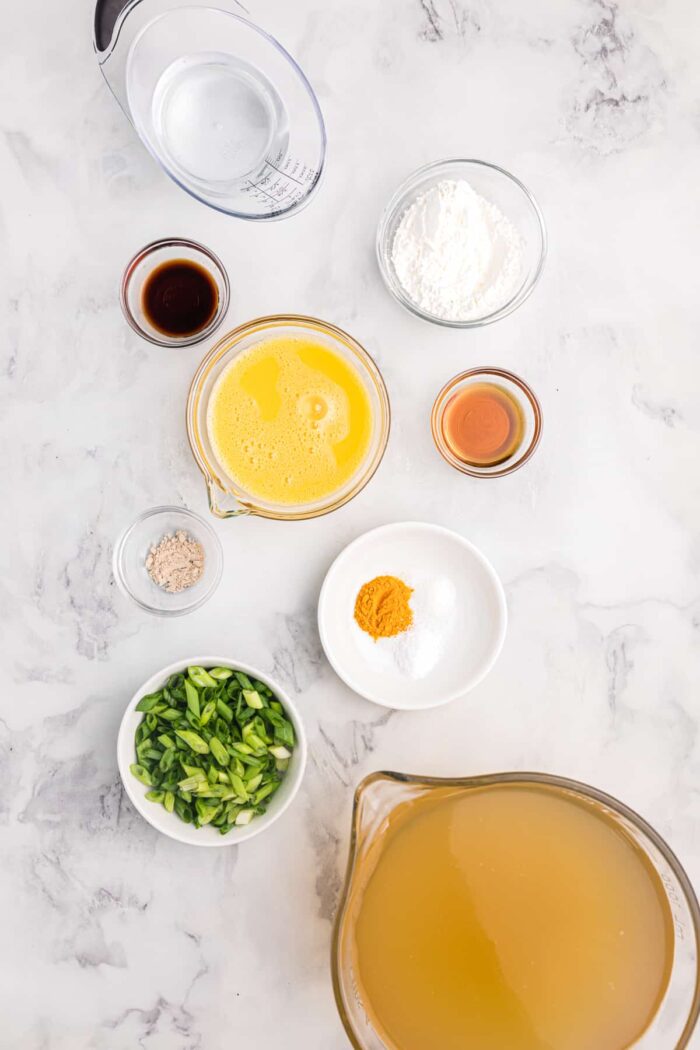 The ingredients for egg drop soup are presented on a white surface.