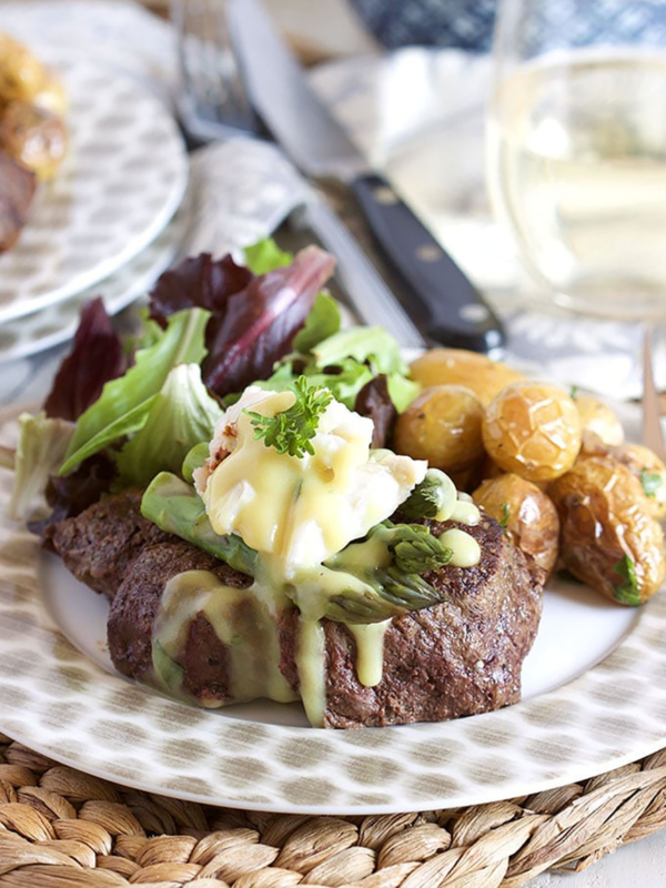 Filet Oscar, or Oscar Style Steak, on a plate with roasted potatoes and salad