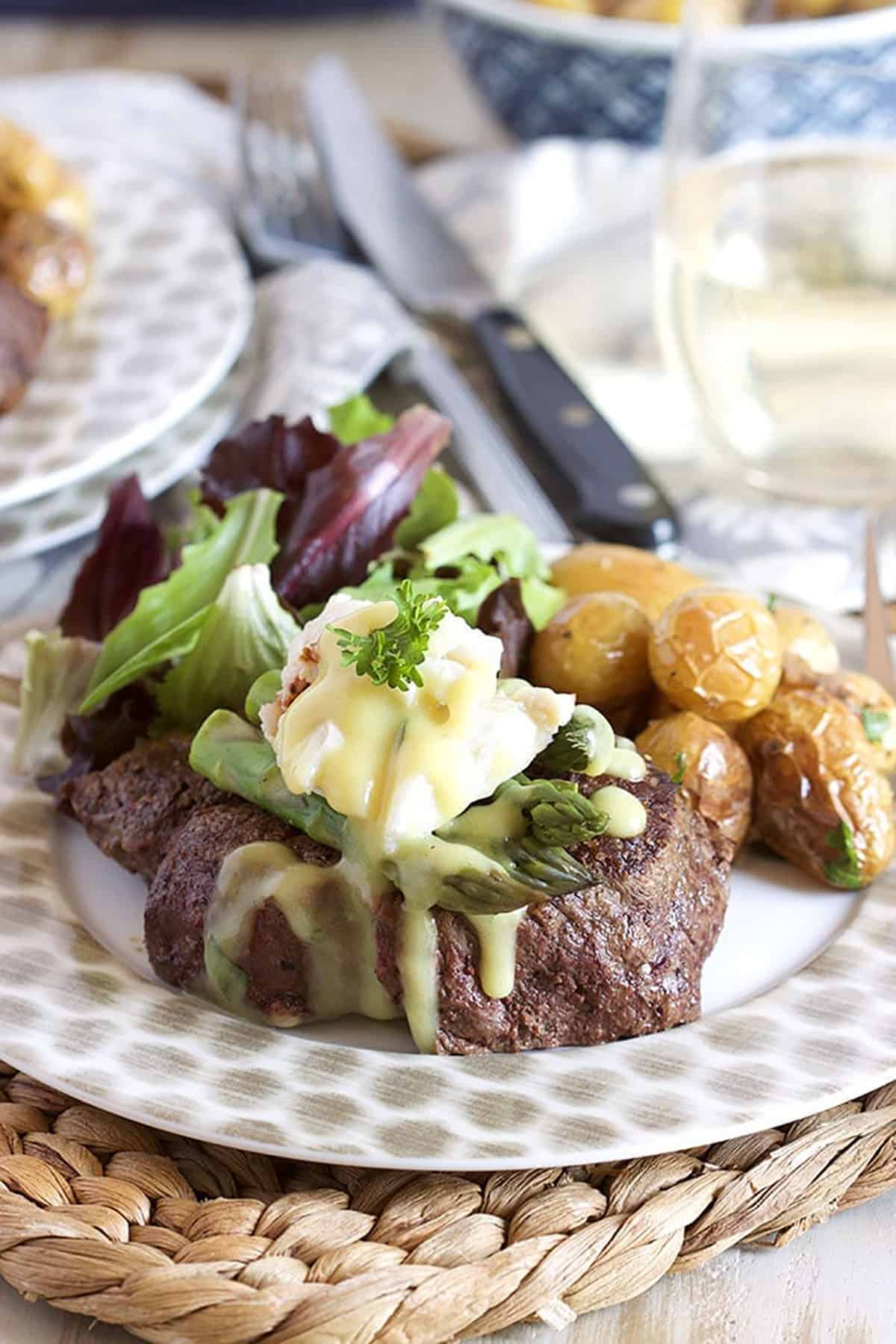 Filet Oscar, or Oscar Style Steak, on a plate with roasted potatoes and salad