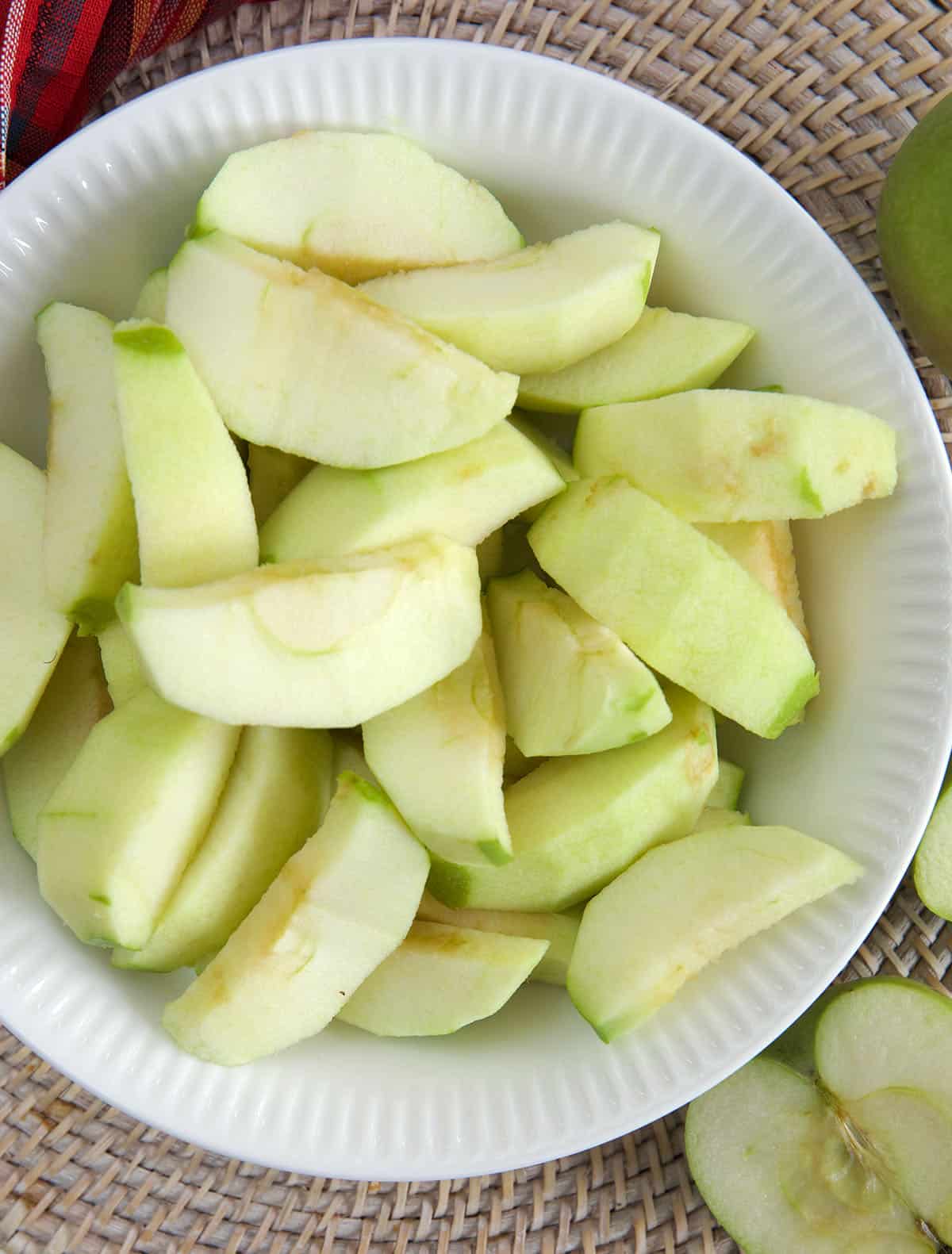 Peeled apples are placed in a bowl.