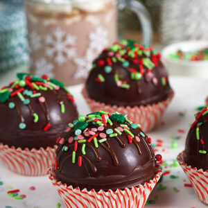Hot chocolate bombs on a marble plate in red and white cupcake wrappers.