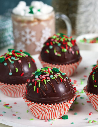 Hot chocolate bombs on a marble plate in red and white cupcake wrappers.