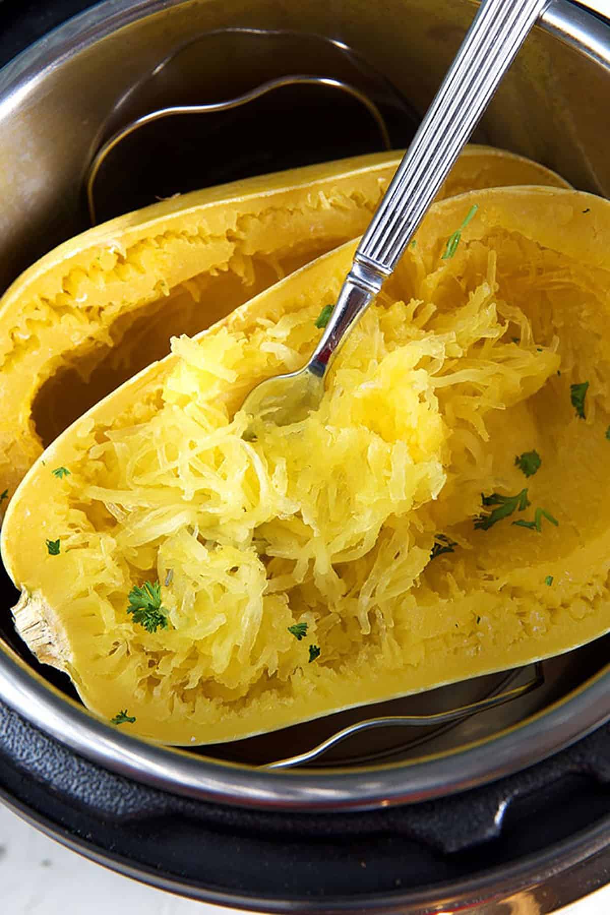 Spaghetti squash is being shredded with a fork. 