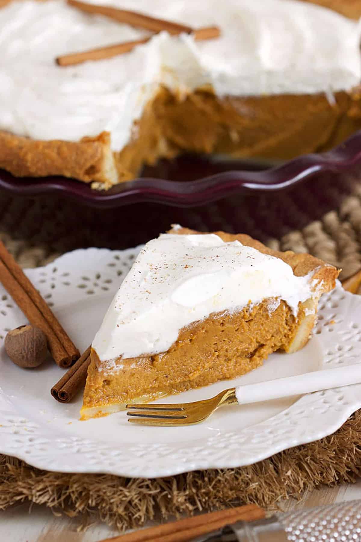 Pumpkin Pie slice on a white plate with a white and gold fork.