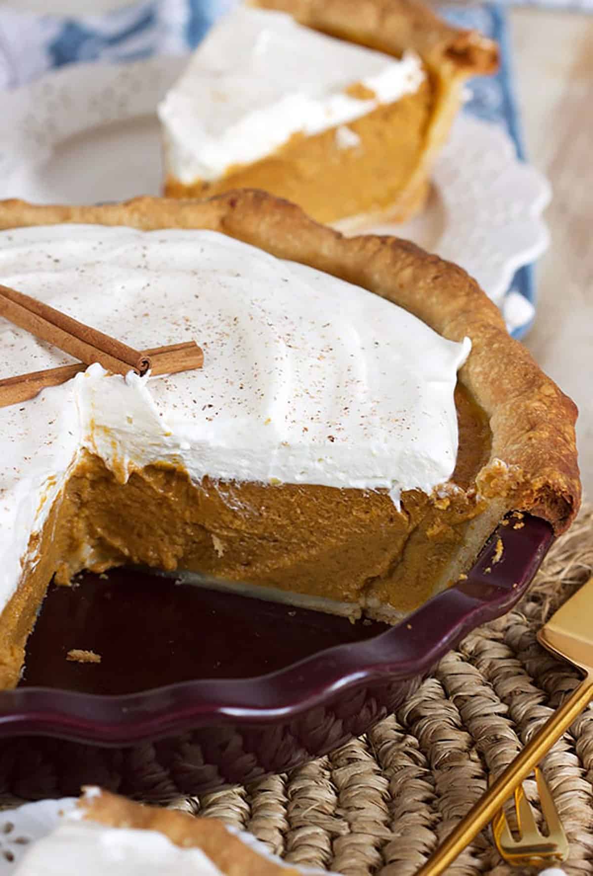whole pumpkin pie with whipped cream on top with a slice cut out of it.