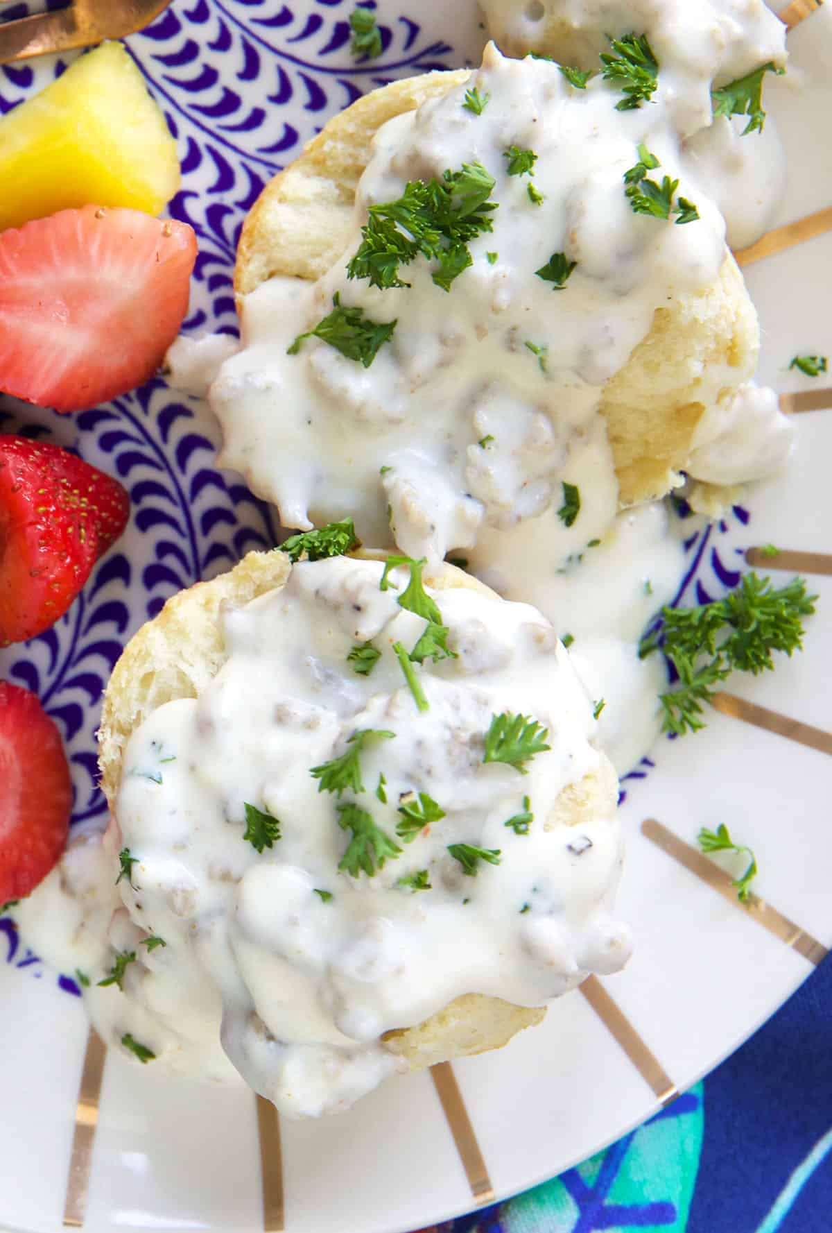 Sausage gravy and fresh parlsey are placed on top of biscuits.