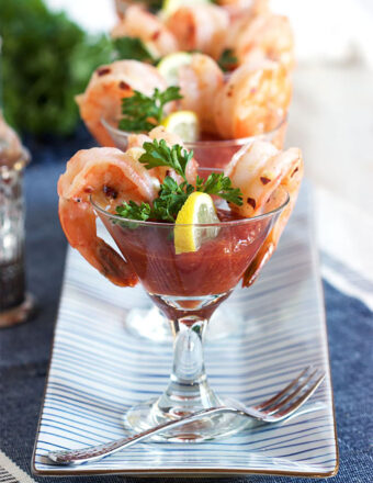 A fork is placed next to a glass fill with shrimp cocktail.