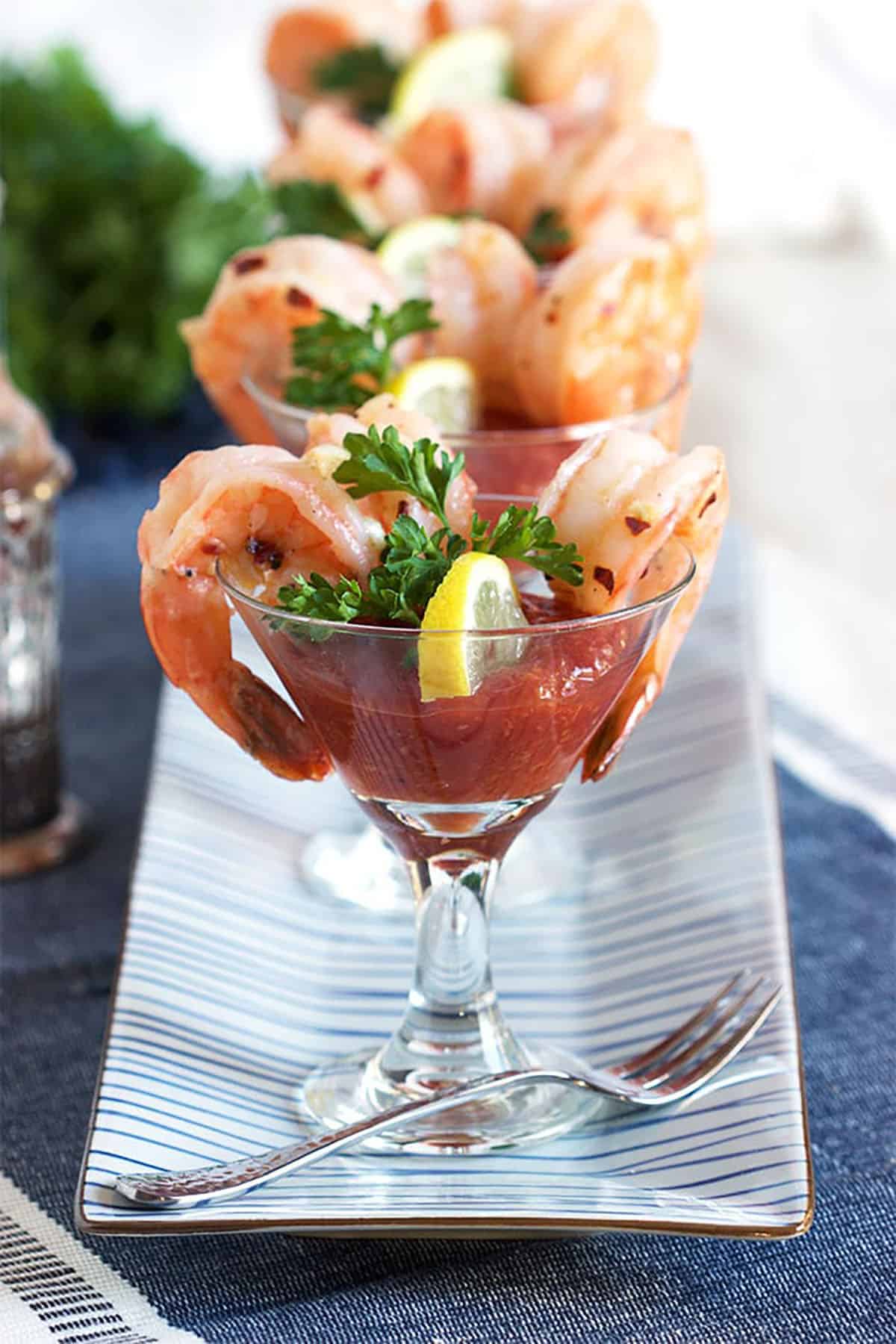 A fork is placed next to a glass fill with shrimp cocktail. 