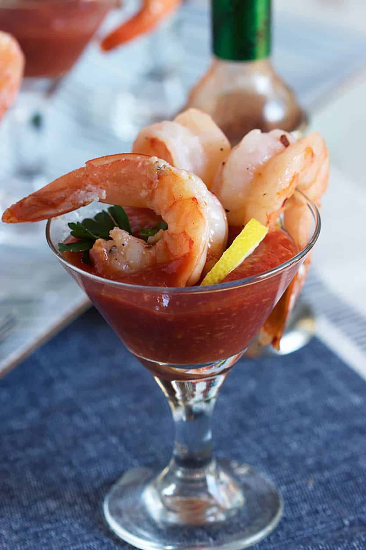 Shrimp are being dunked into cocktail sauce. 