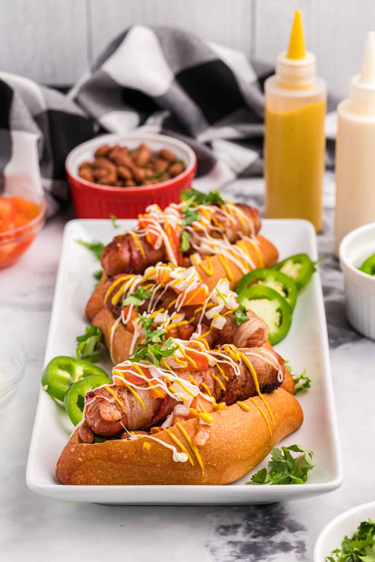 Several hot dogs are placed on a white serving plate.