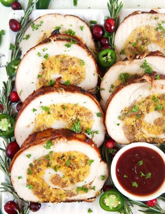 slices of turkey roulade stuffed with cornbread arranged on a platter with cranberry bbq sauce.