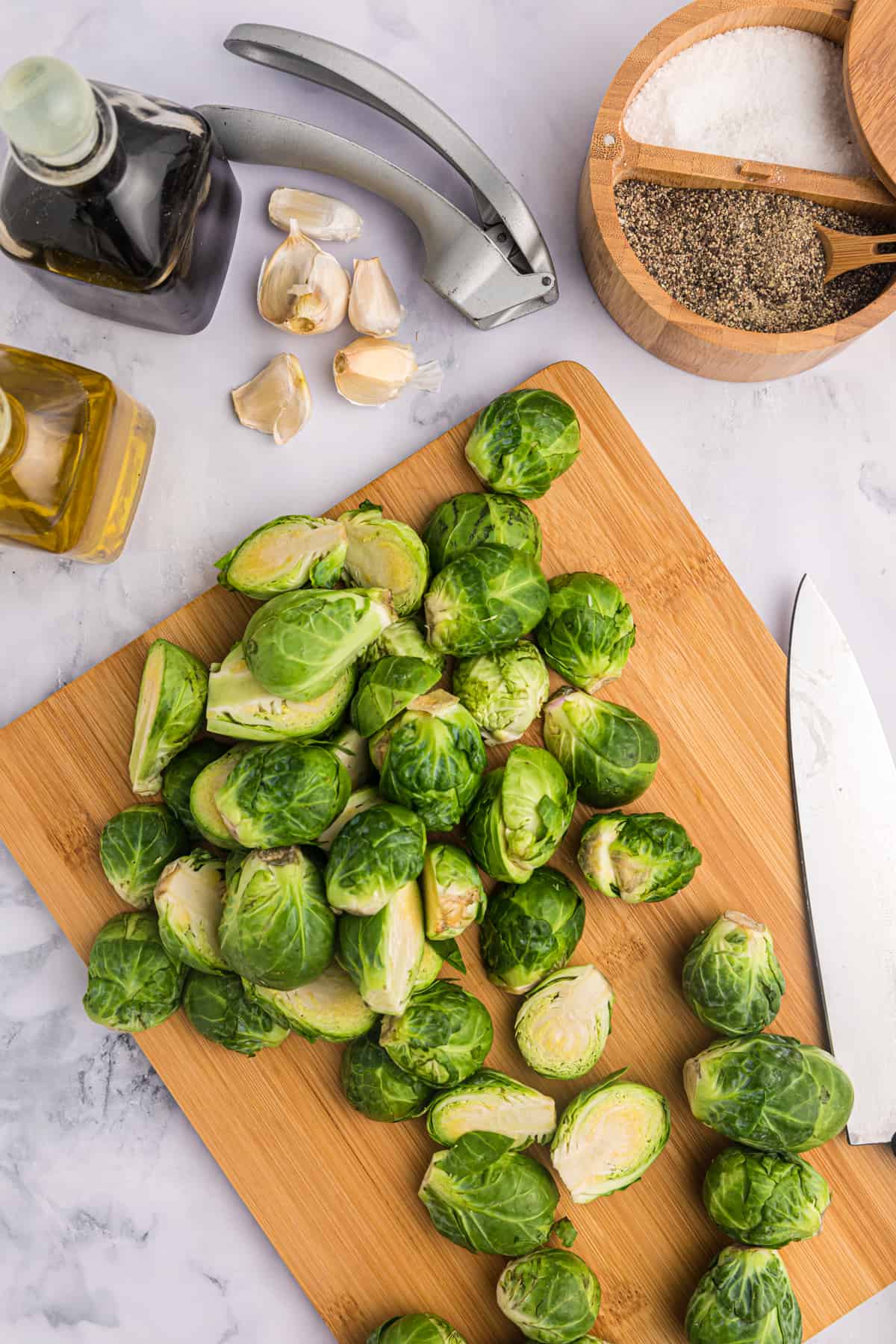 Brussels sprouts are being chopped on a wooden cutting board.