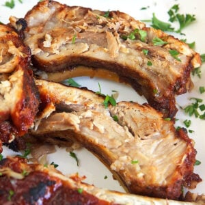 Close up of cut bbq ribs on a white platter.