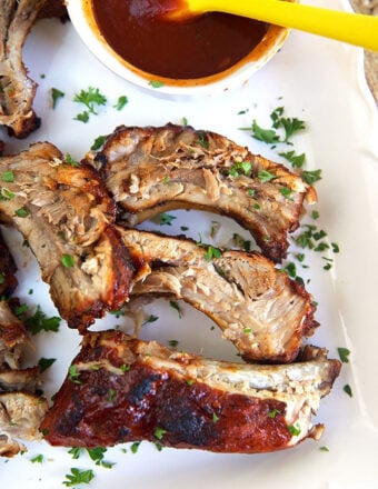 overhead shot of bbq ribs on a white platter.