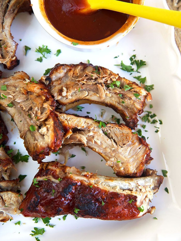 overhead shot of bbq ribs on a white platter.