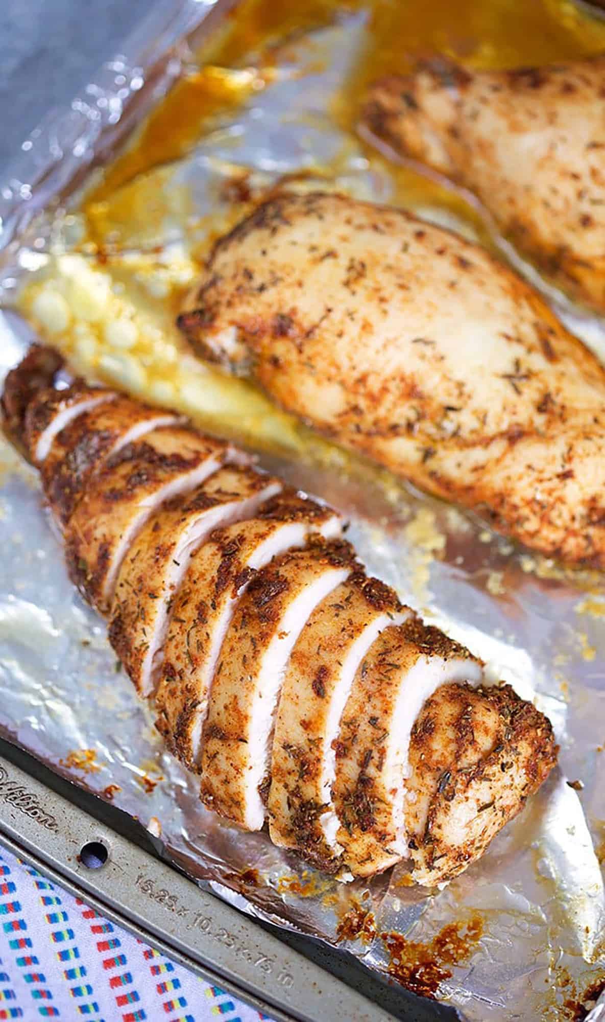 Sliced baked chicken breast on a baking sheet with foil.