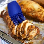sliced baked chicken breast with a blue basting brush on the top
