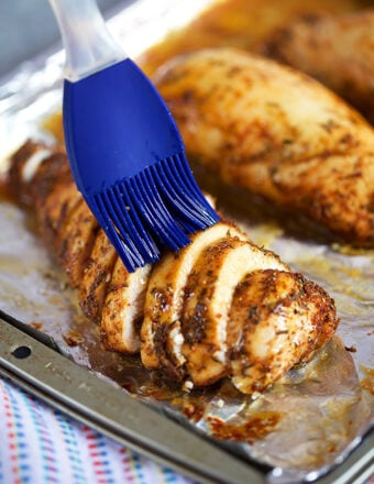 sliced baked chicken breast with a blue basting brush on the top