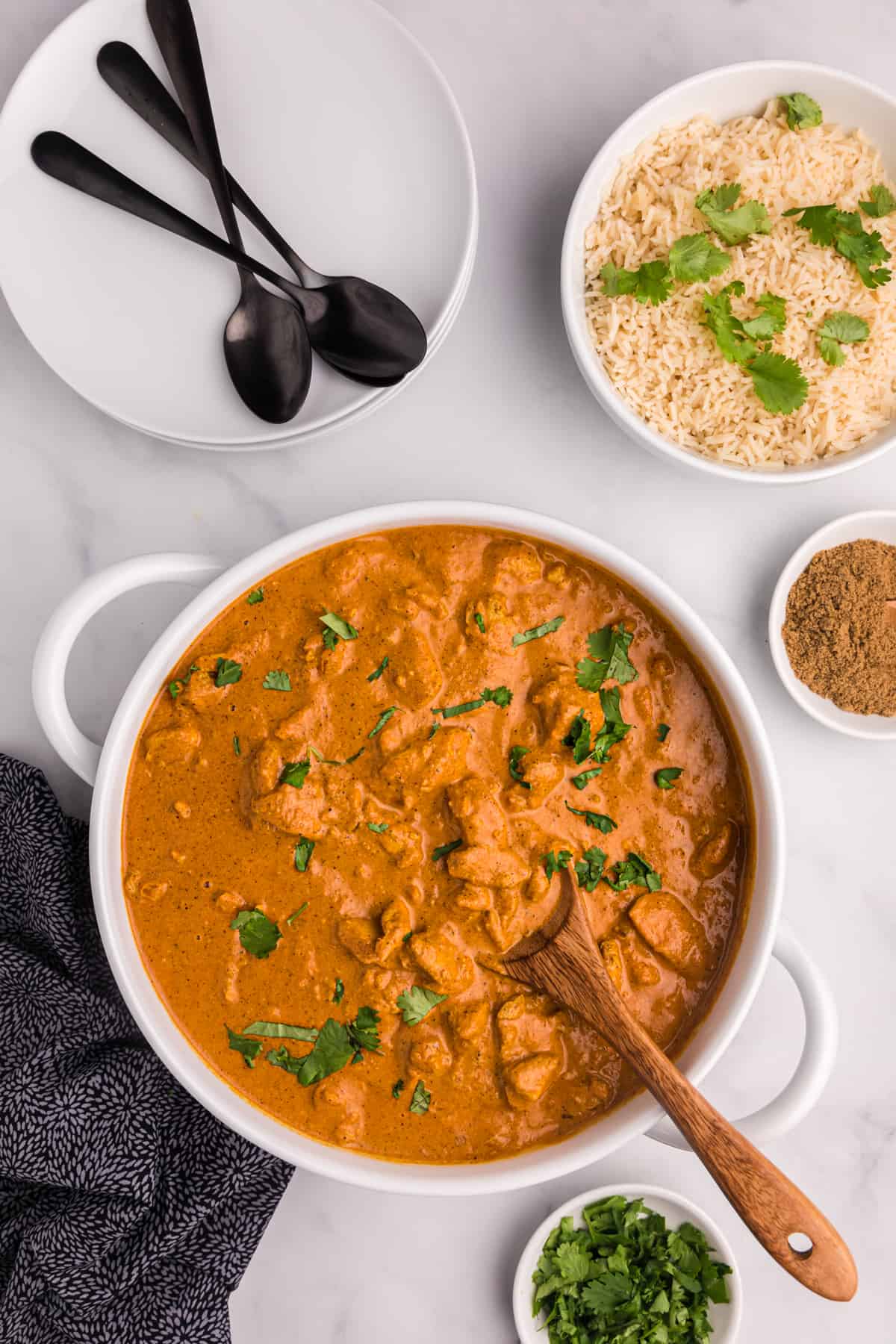 A white pot is filled with cooked chicken tikka masala.