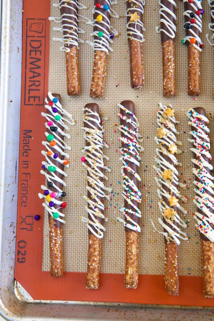 Chocolate covered pretzels are evenly spread across a silicone mat.