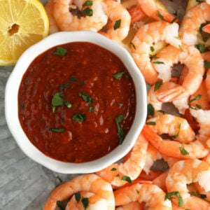 Overhead view of cocktail sauce in bowl on platter of shrimp