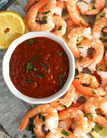 Overhead view of cocktail sauce in bowl on platter of shrimp