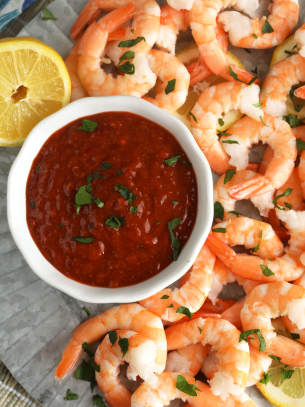 Overhead view of cocktail sauce in bowl on platter of shrimp