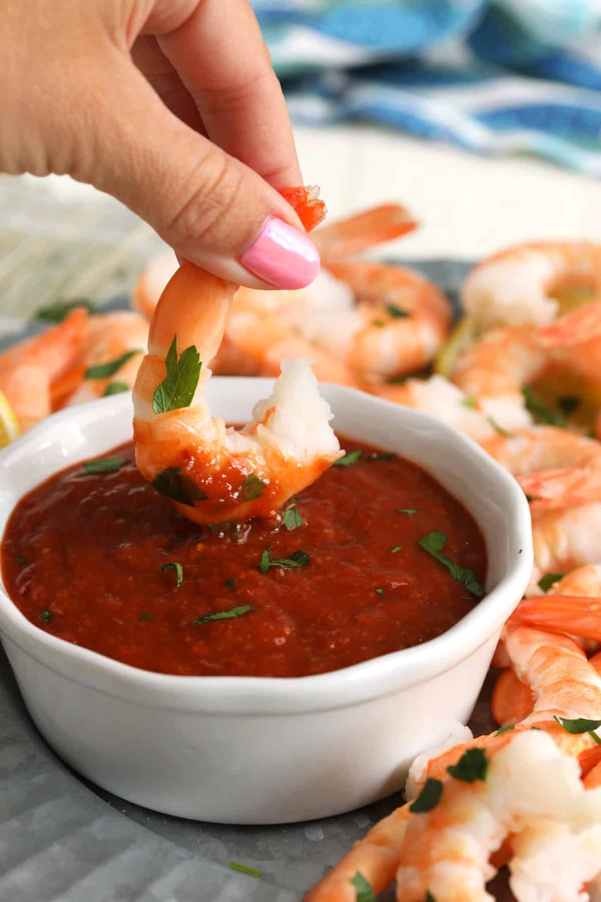 Dipping shrimp into bowl of cocktail sauce