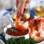 Shrimp being dipped into homemade cocktail sauce