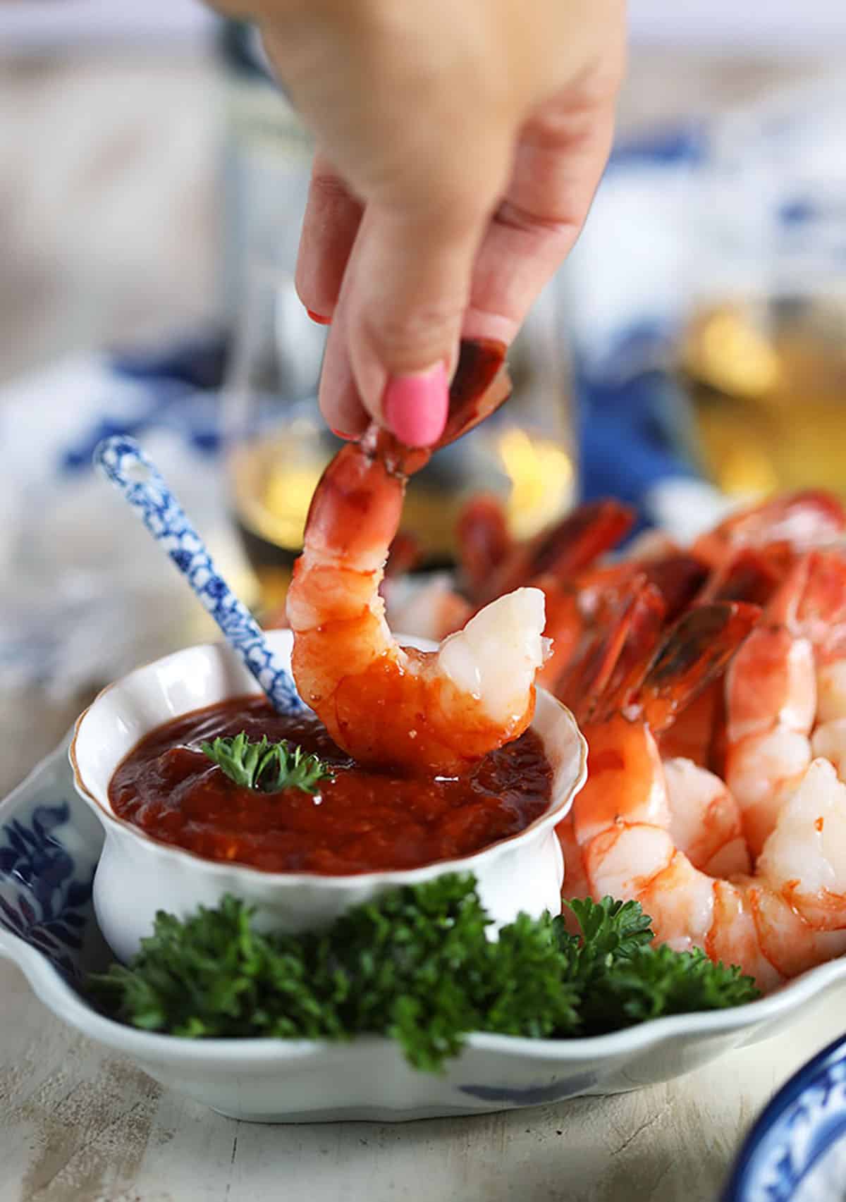 Shrimp being dipped into homemade cocktail sauce 
