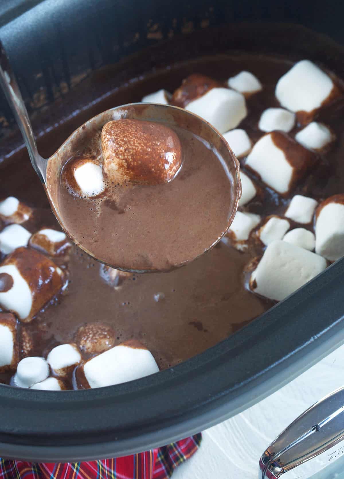 A ladel is scooping up a small serving of hot chocolate and marshmallows. 