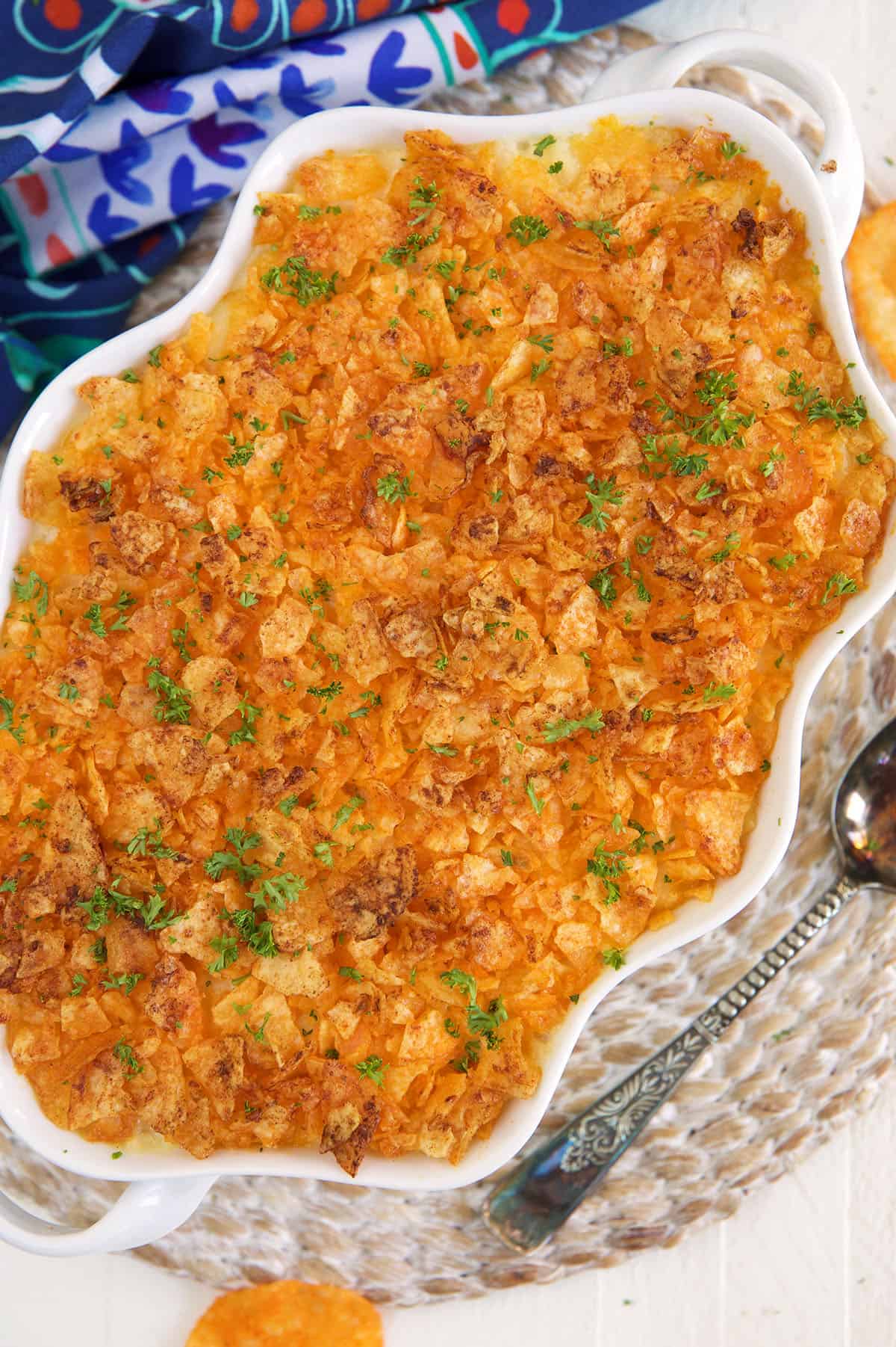 A white casserole dish is filled with baked funeral potatoes.