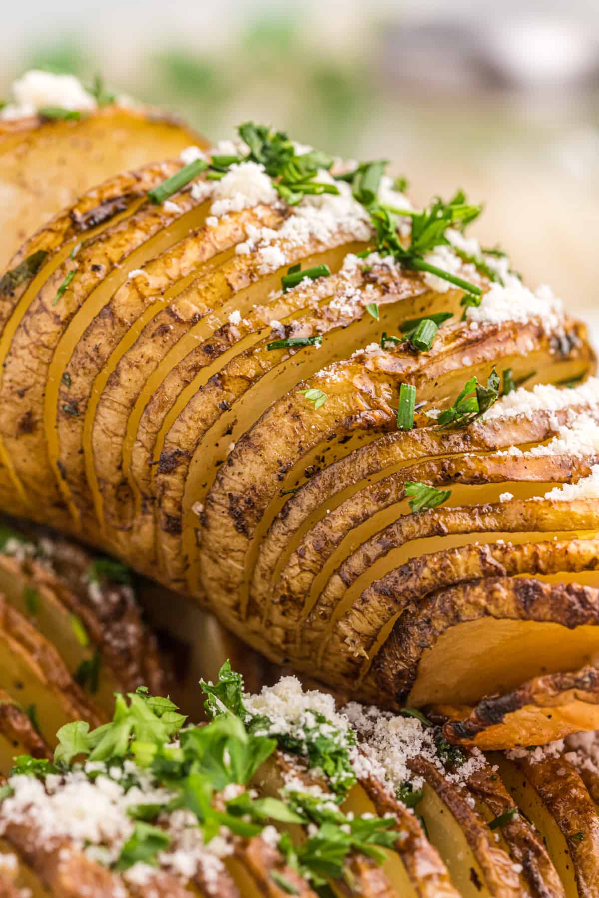 A garnished and baked Hasselback Potato is ready to eat.