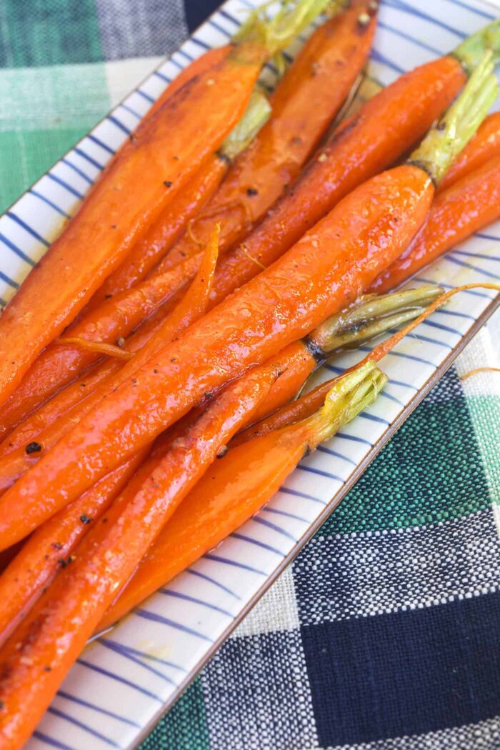 A striped plate is topped with cooked carrots.