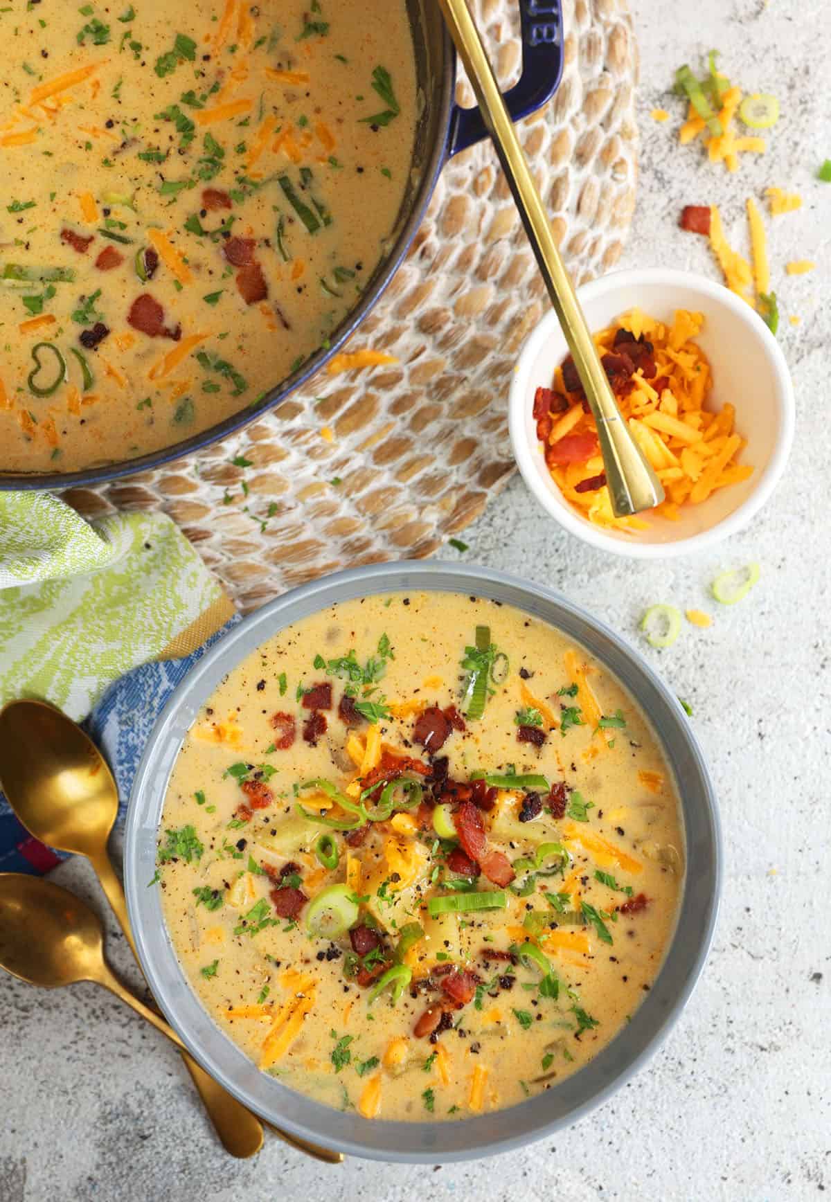 Overhead view of loaded baked potato soup in bowl and slow cooker