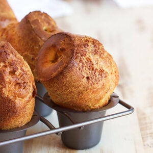 Popovers in a popover pan on a wood background.