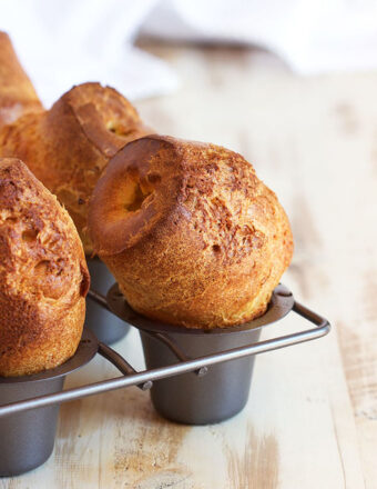 Popovers in a popover pan on a wood background.