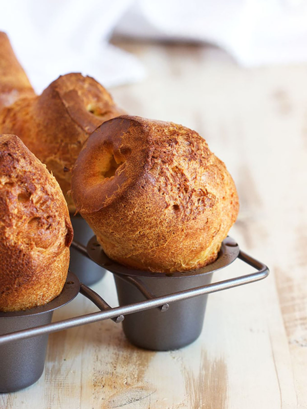Popovers in a popover pan on a wood background.