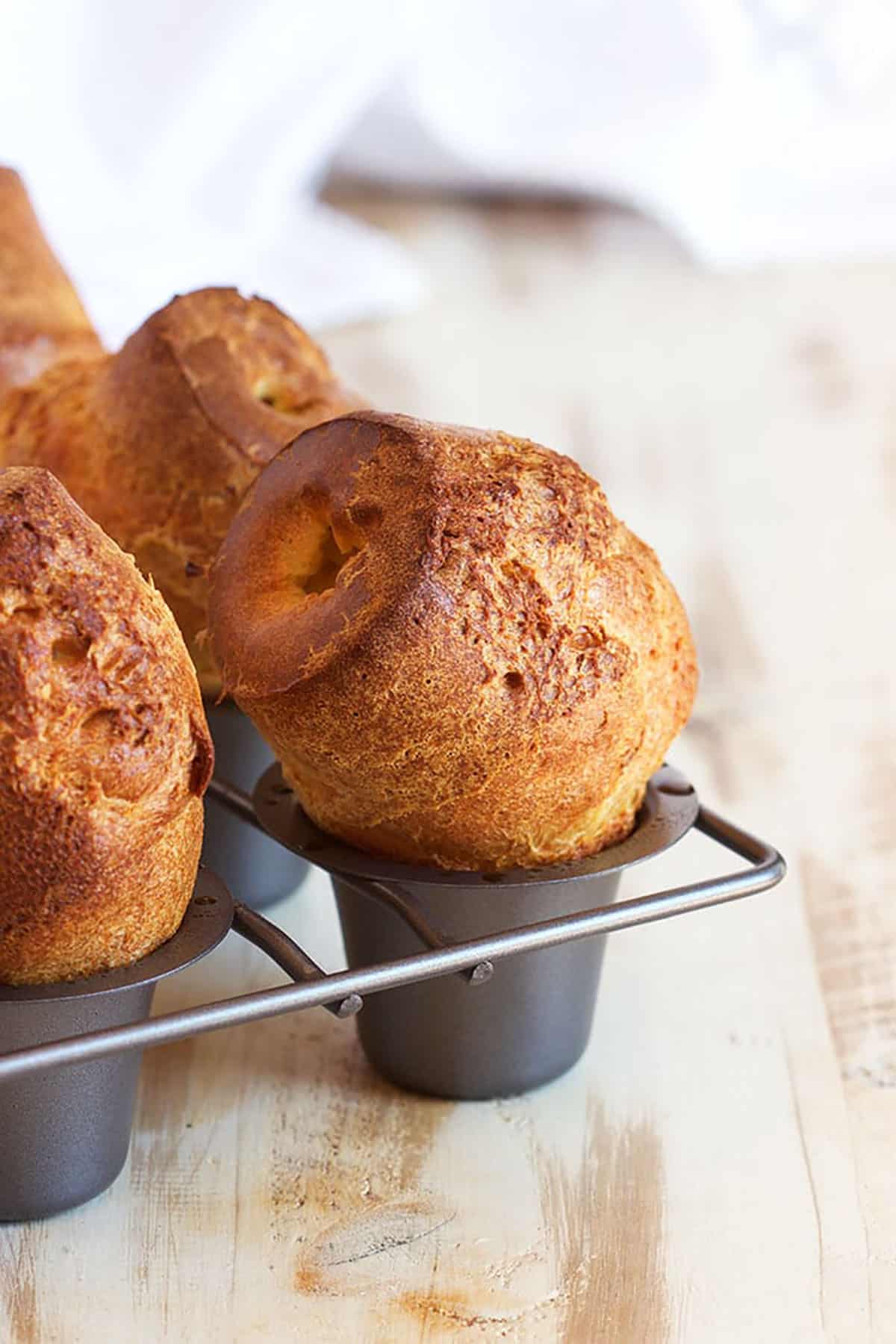 Popovers in a popover pan on a wood background.