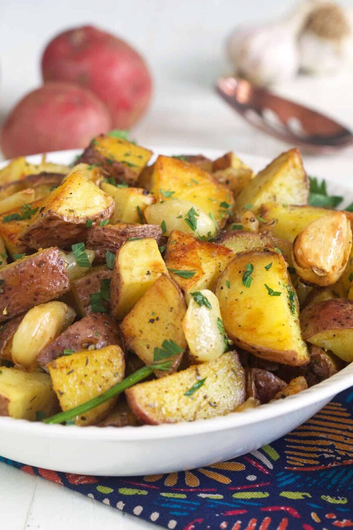 A white bowl is filled with roasted potatoes. 