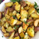 A bowl of roasted potatoes is garnished with parsley.