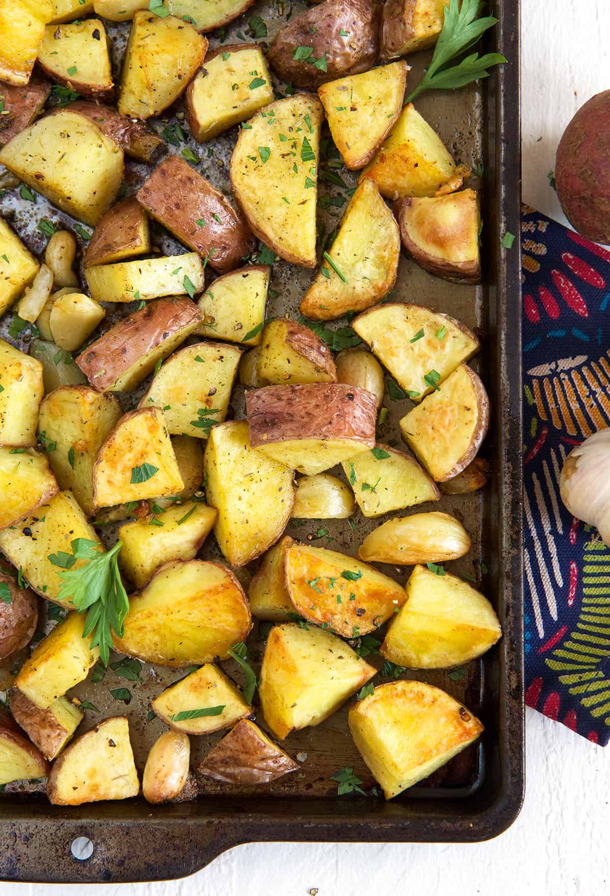 Potatoes have been roasted and garnished on a baking sheet.