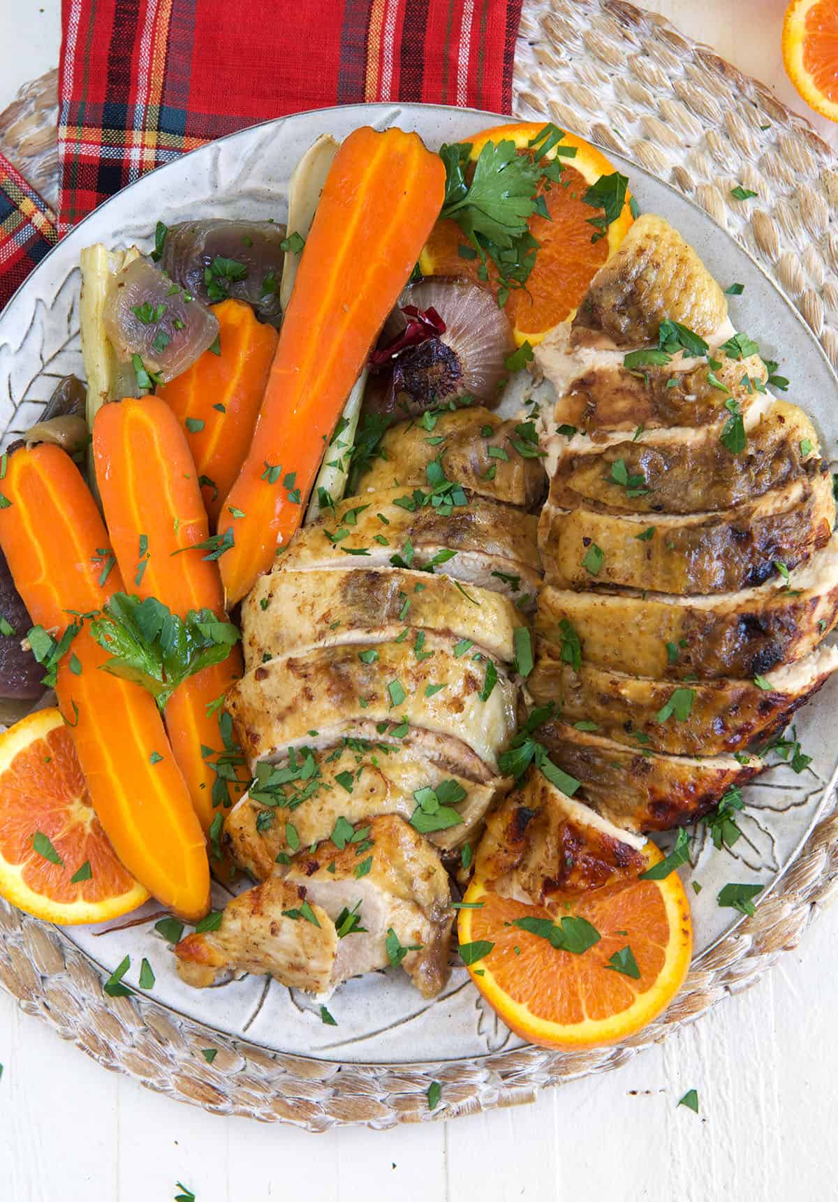 Sliced turkey breast is placed on a plate with cooked carrots.