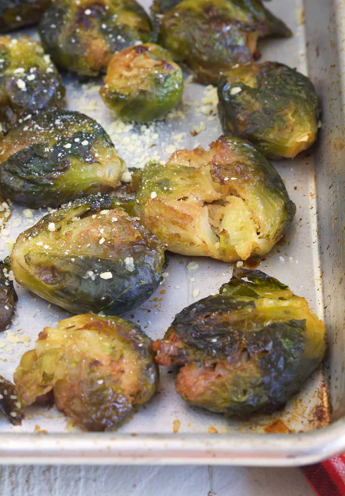 A baking sheet is topped with a number of smashed brussels sprouts. 